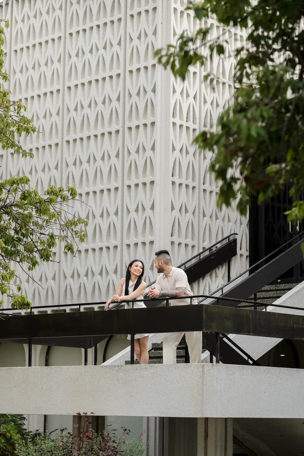 Alana and Colin smiling at one another on a terrace.