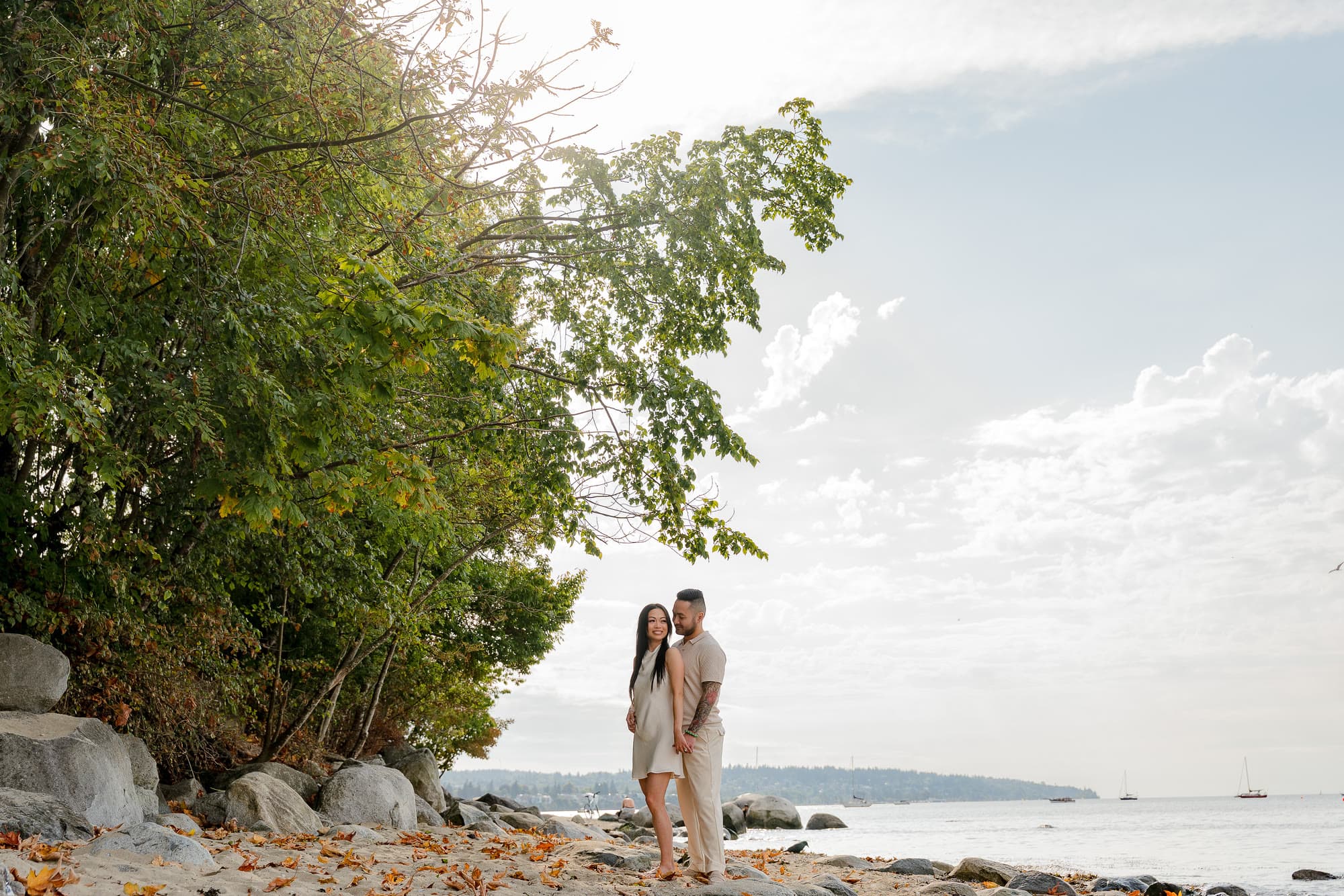 Alana and Colin standing together beneath the trees at the water’s edge.