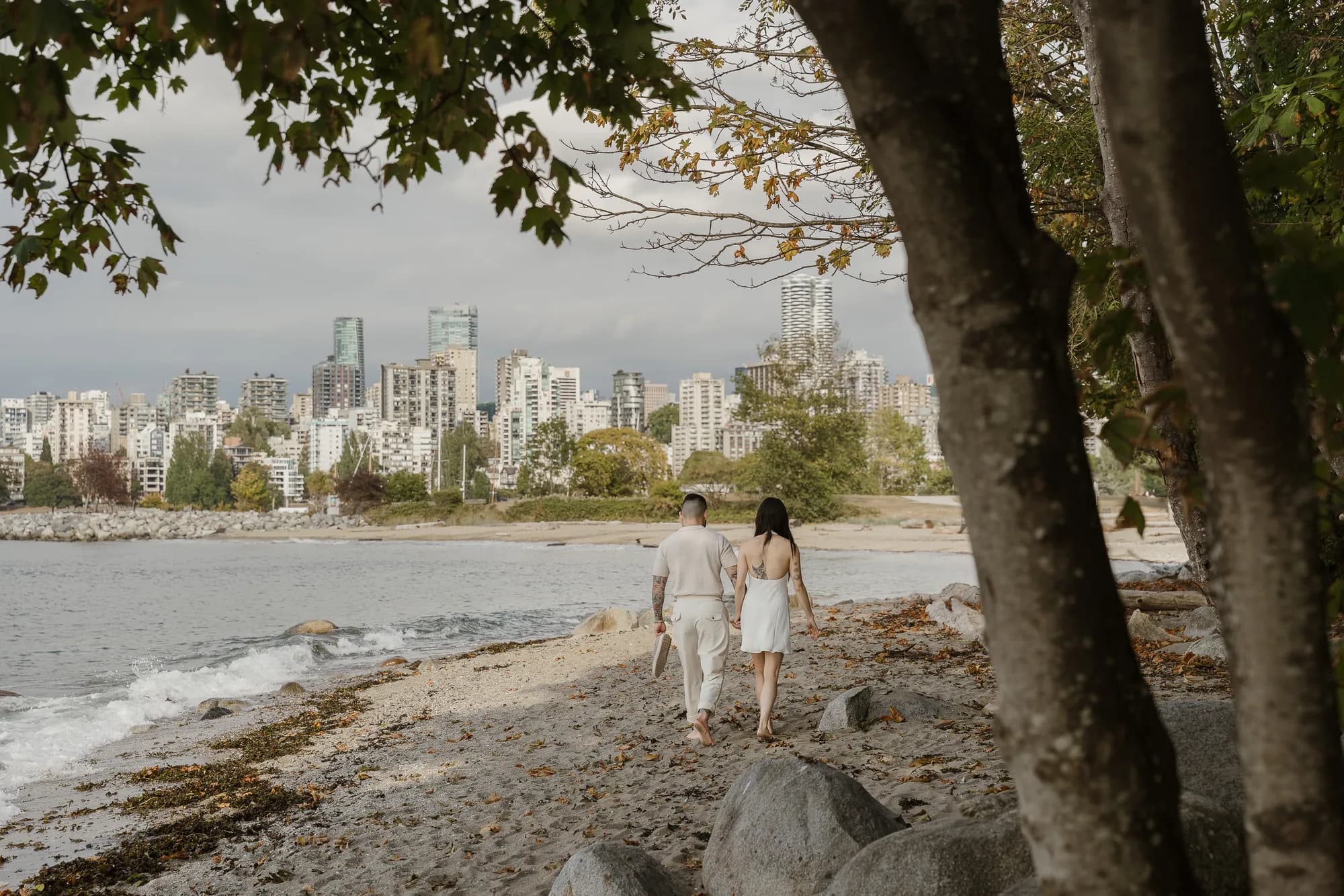 Alana and Colin walking hand in hand along the shore.